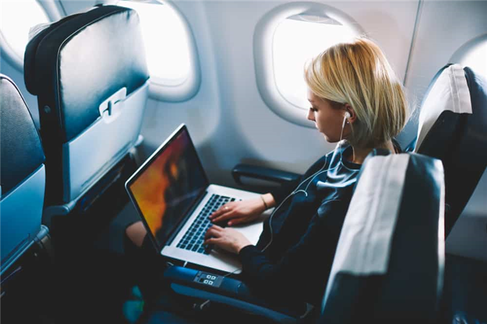 Женщина использует свой ноутбук в самолете