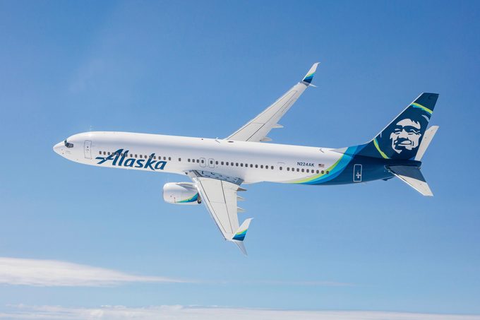 Самолет Alaska Airlines в полете на фоне голубого неба