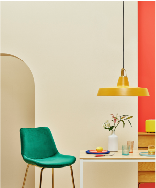 изображение зеленого стула рядом с накрытым столом и золотой лампы, свисающей с потолка. 