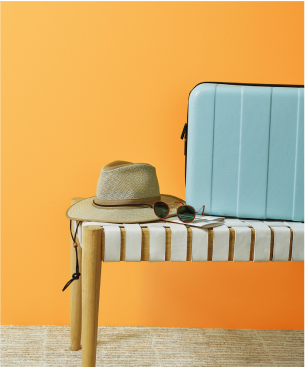 Изображение шляпы, солнцезащитных очков и чемодана на пуфике. 