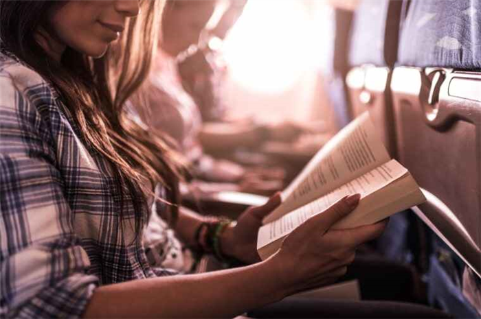 Изображение: Женщина читает книгу в самолете