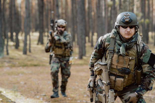 Портрет бородатого солдата средних лет в военной форме лесного типа и каске с наушниками