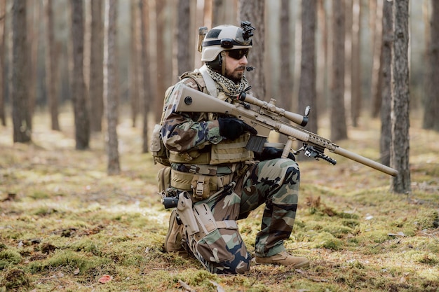 Портрет бородатого солдата средних лет в военной форме лесного типа и каске с наушниками