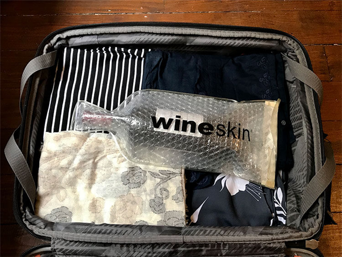 Дженнифер использует WineSkin, чтобы запечатать бутылку вина в чемодане