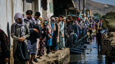 Афганцы пробираются по затопленной улице в сторону аэропорта Кабула