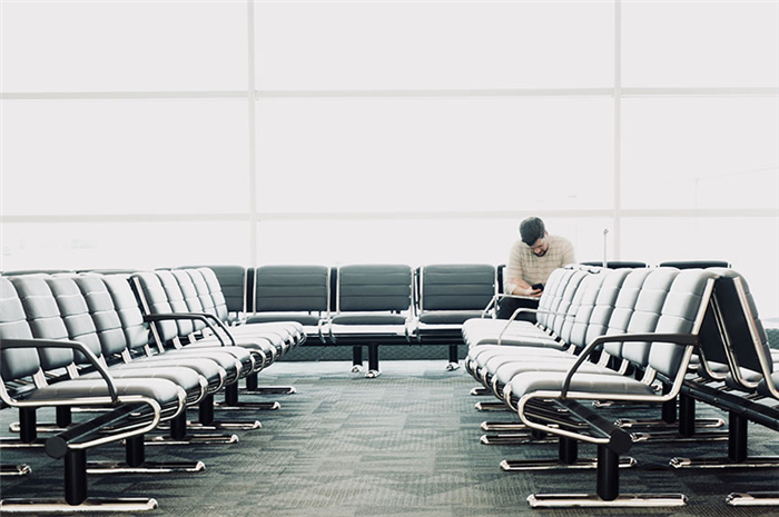 Одинокий мужчина сидит в аэропорту возле выхода на посадку