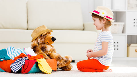 Маленькая девочка играет со своей мягкой игрушкой.