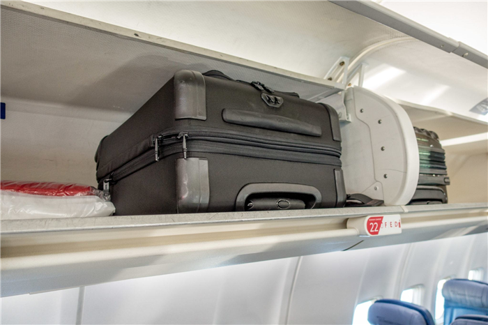 Два ручных чемодана в подвесной корзине самолета