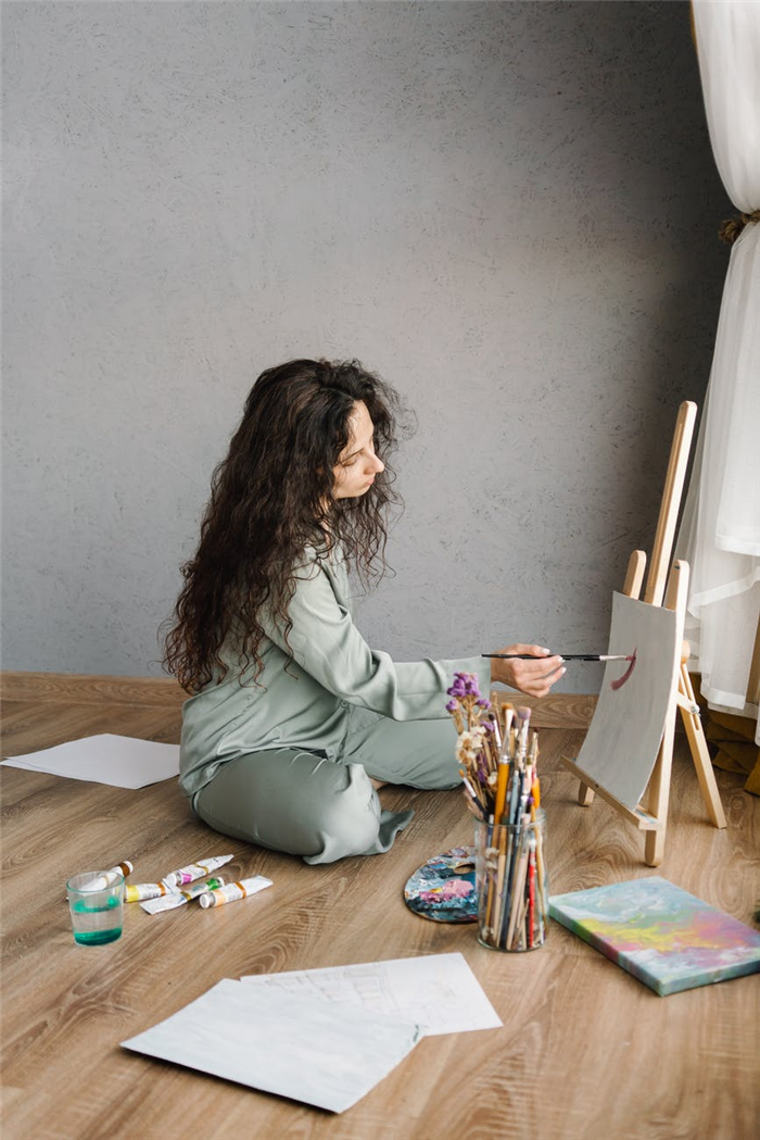 женщина рисует, сидя на полу