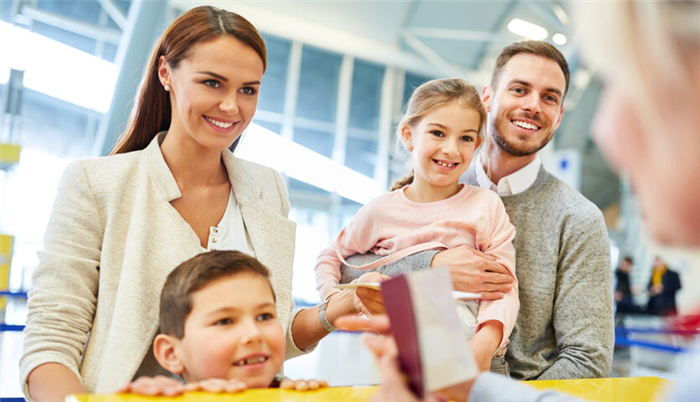 счастливой семье на стойке регистрации в терминале аэропорта.